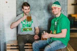 Two men enjoying beer and celebrating St. Patrick's Day indoors.
