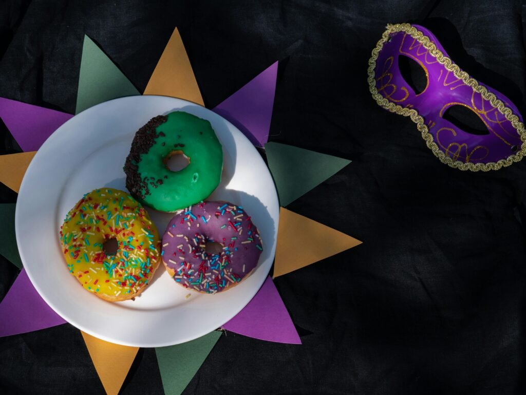 Colorful donuts and a masquerade mask celebrating Mardi Gras on a festive background.