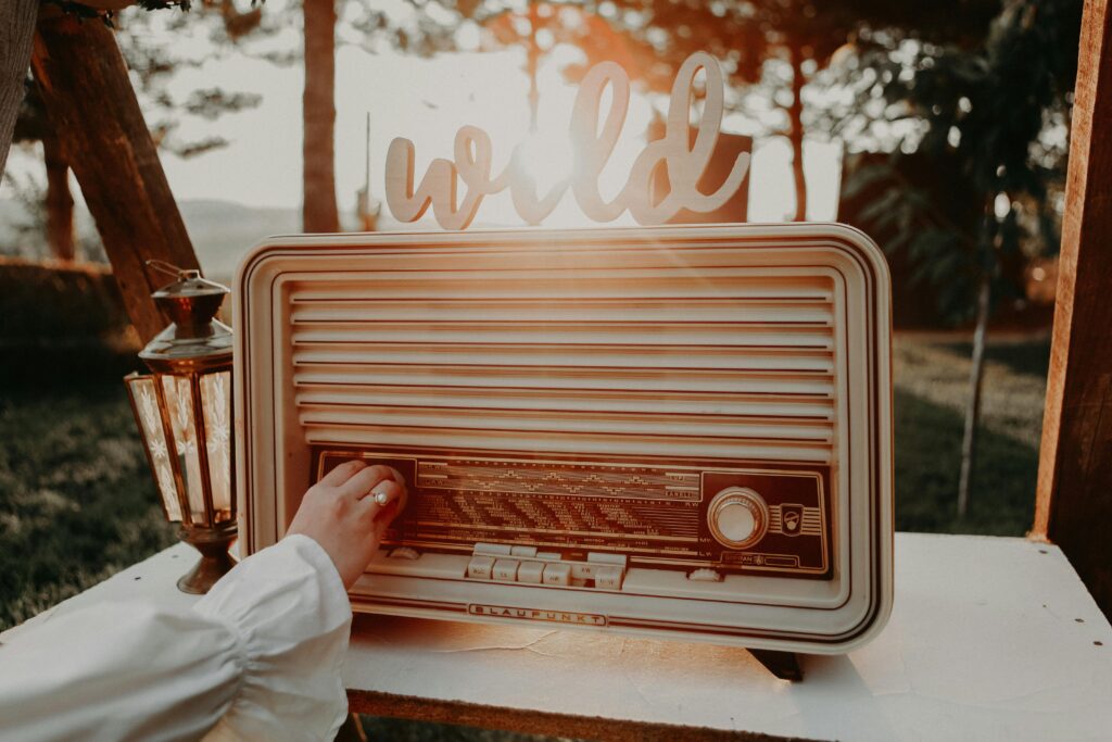Vintage radio being tuned by a hand with warm sunlight, creating a nostalgic feel.